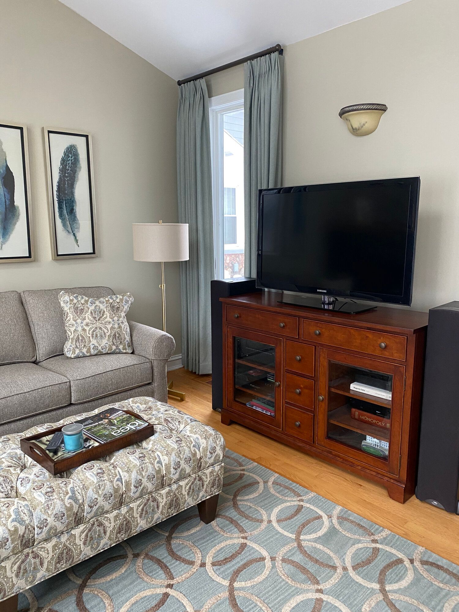 A living room with a couch , ottoman , coffee table and television.