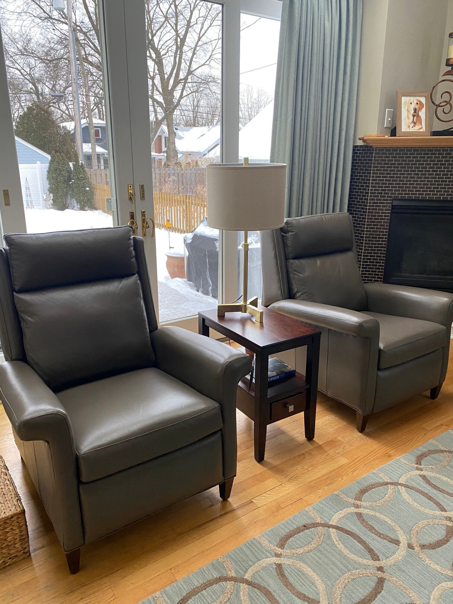 A living room with two chairs , a table , a lamp and a fireplace.