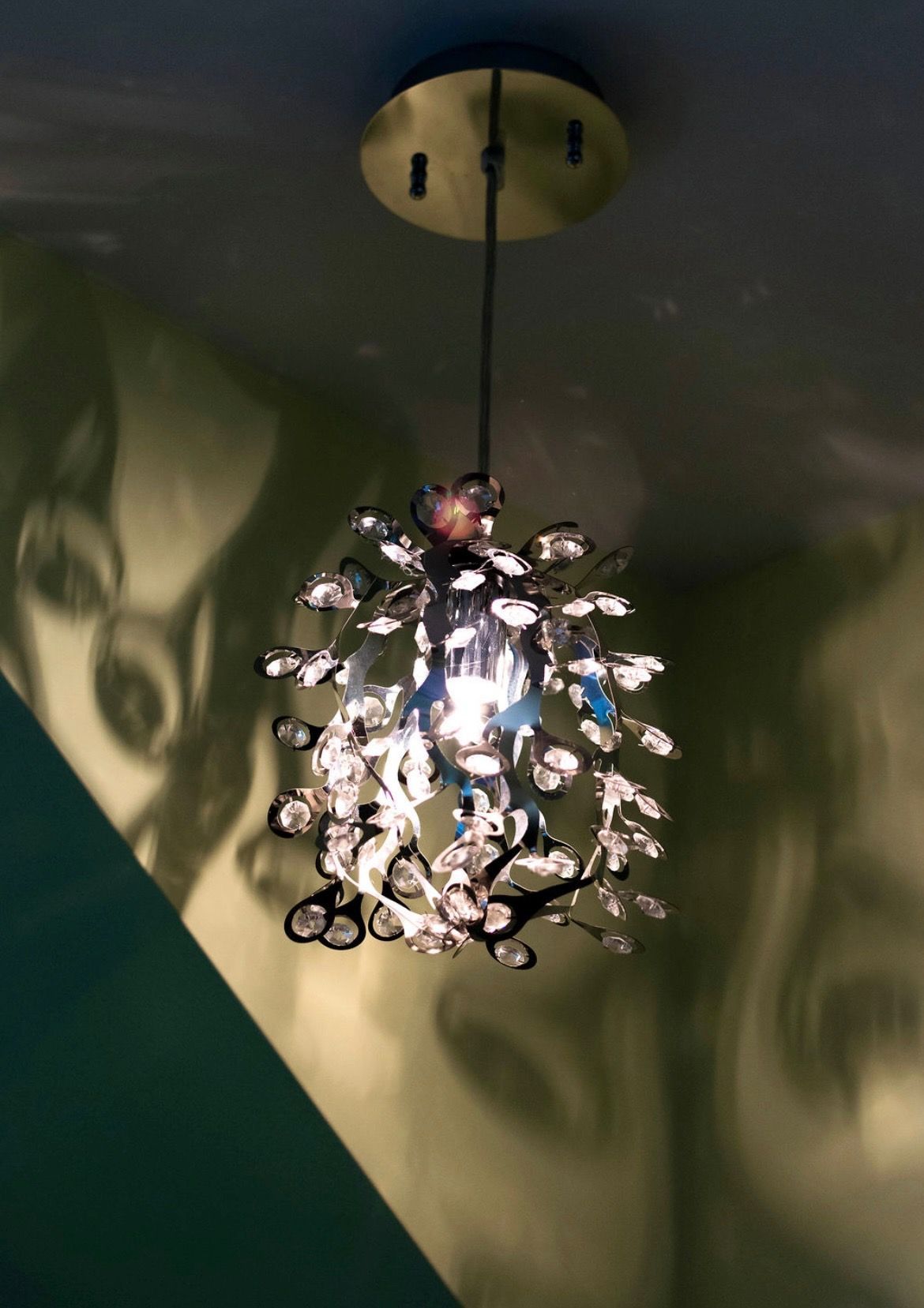 A crystal pendant light illuminates a corner, casting decorative shadows on the surrounding walls.