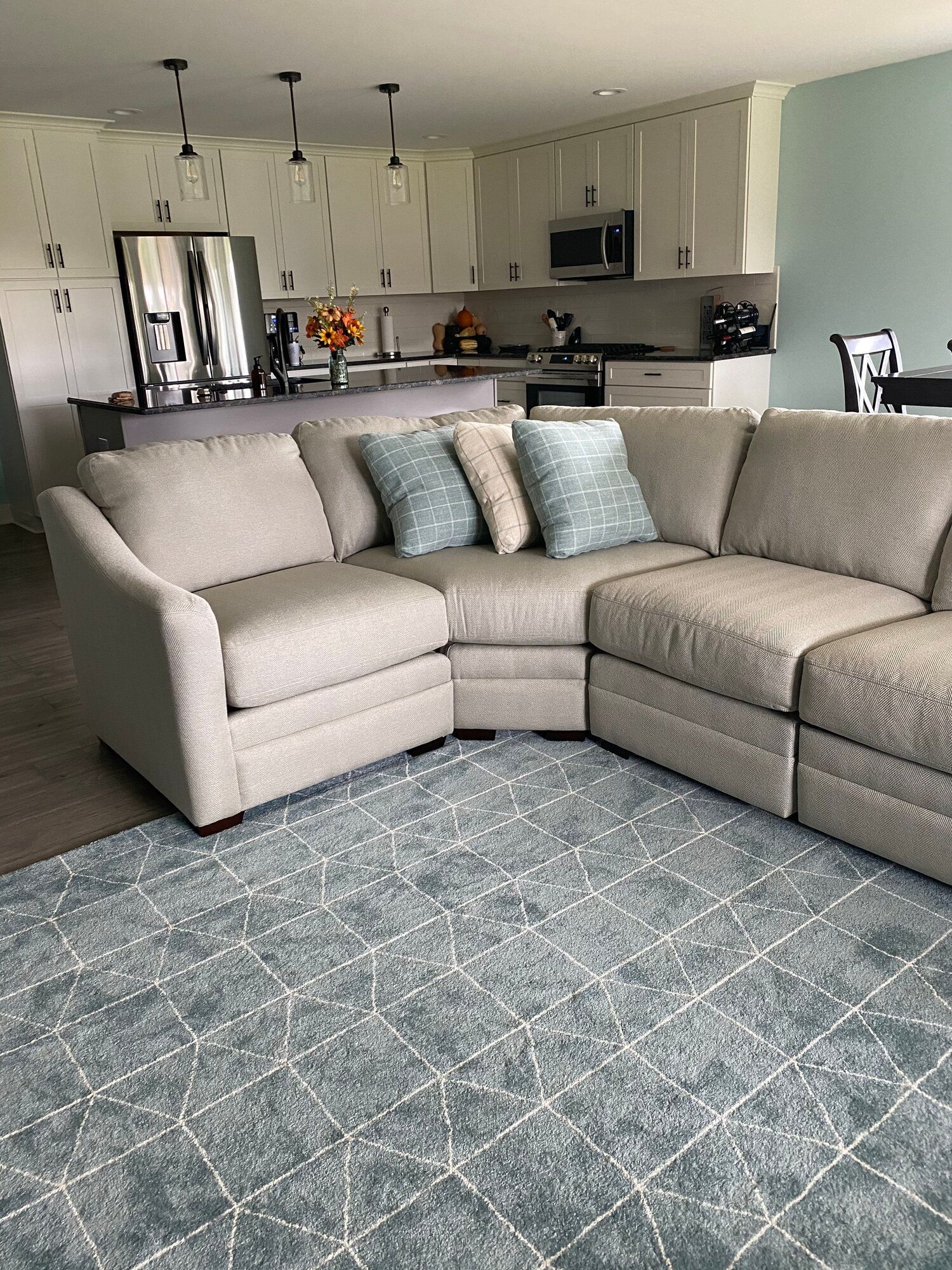 A living room with a sectional couch and a rug.