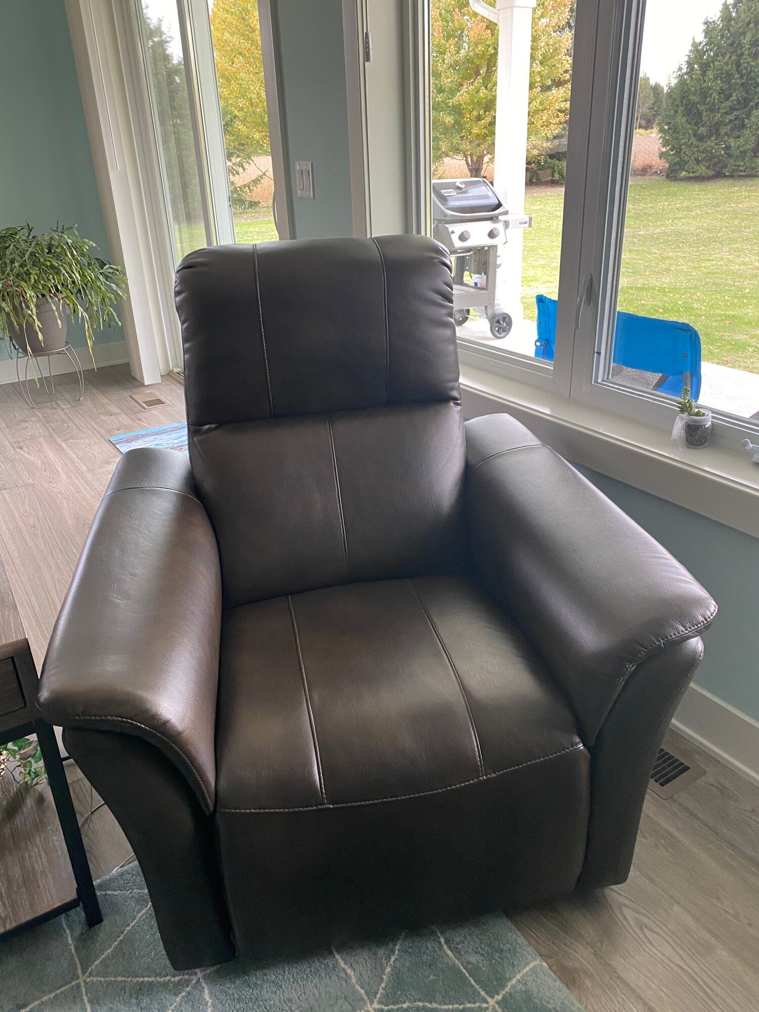 A brown leather recliner is sitting in a living room next to a window.