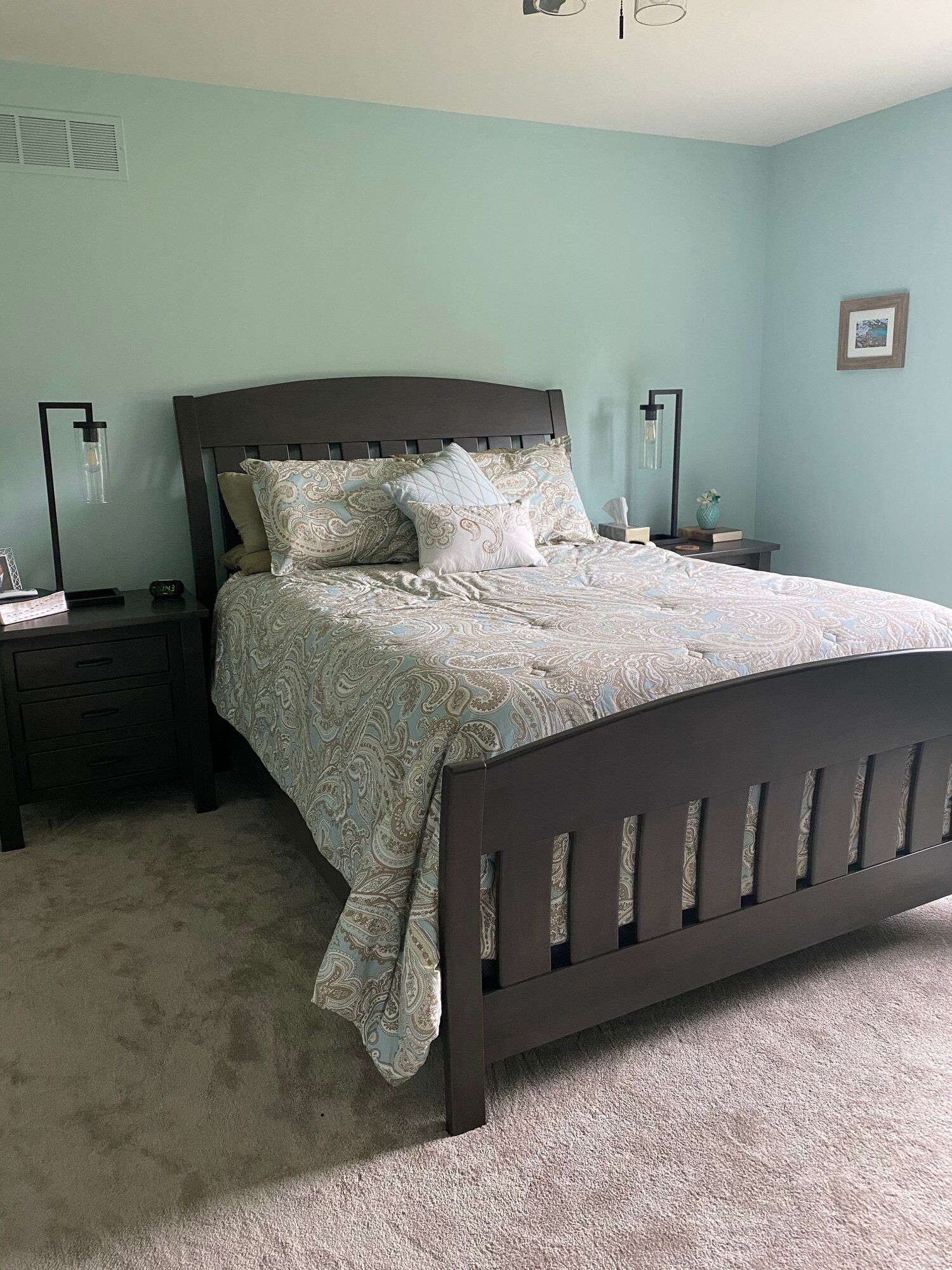 A bedroom with a bed , nightstands , and blue walls.