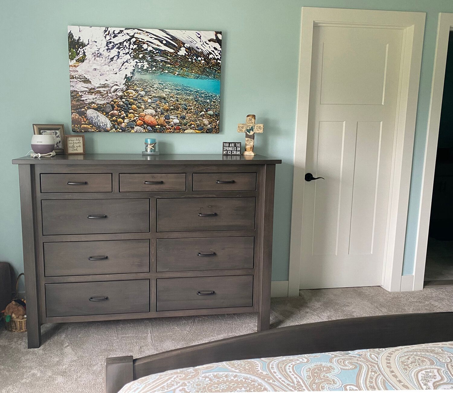 A bedroom with a dresser and a picture on the wall above it