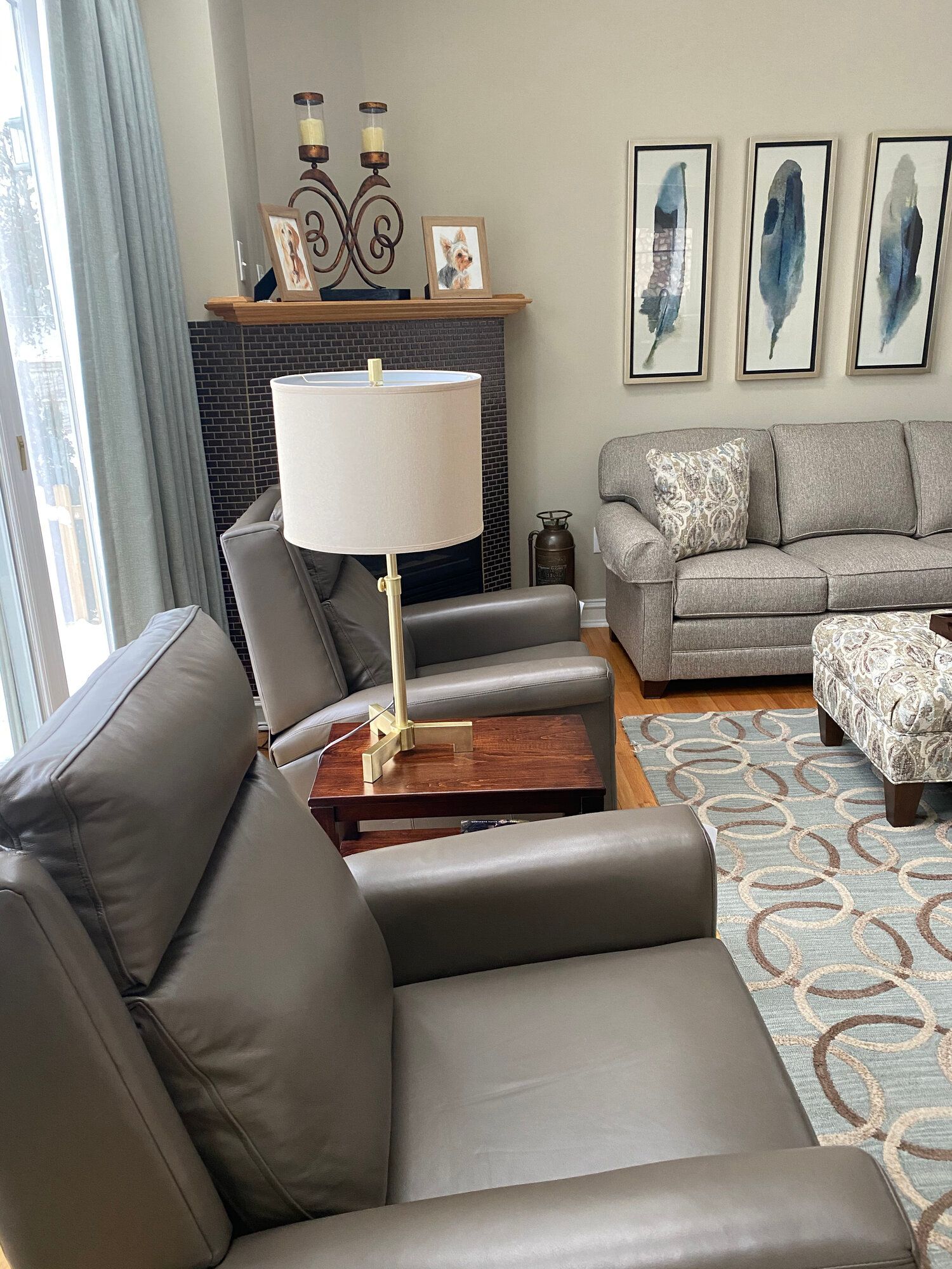 A living room with a couch , chairs , ottoman , lamp and fireplace.