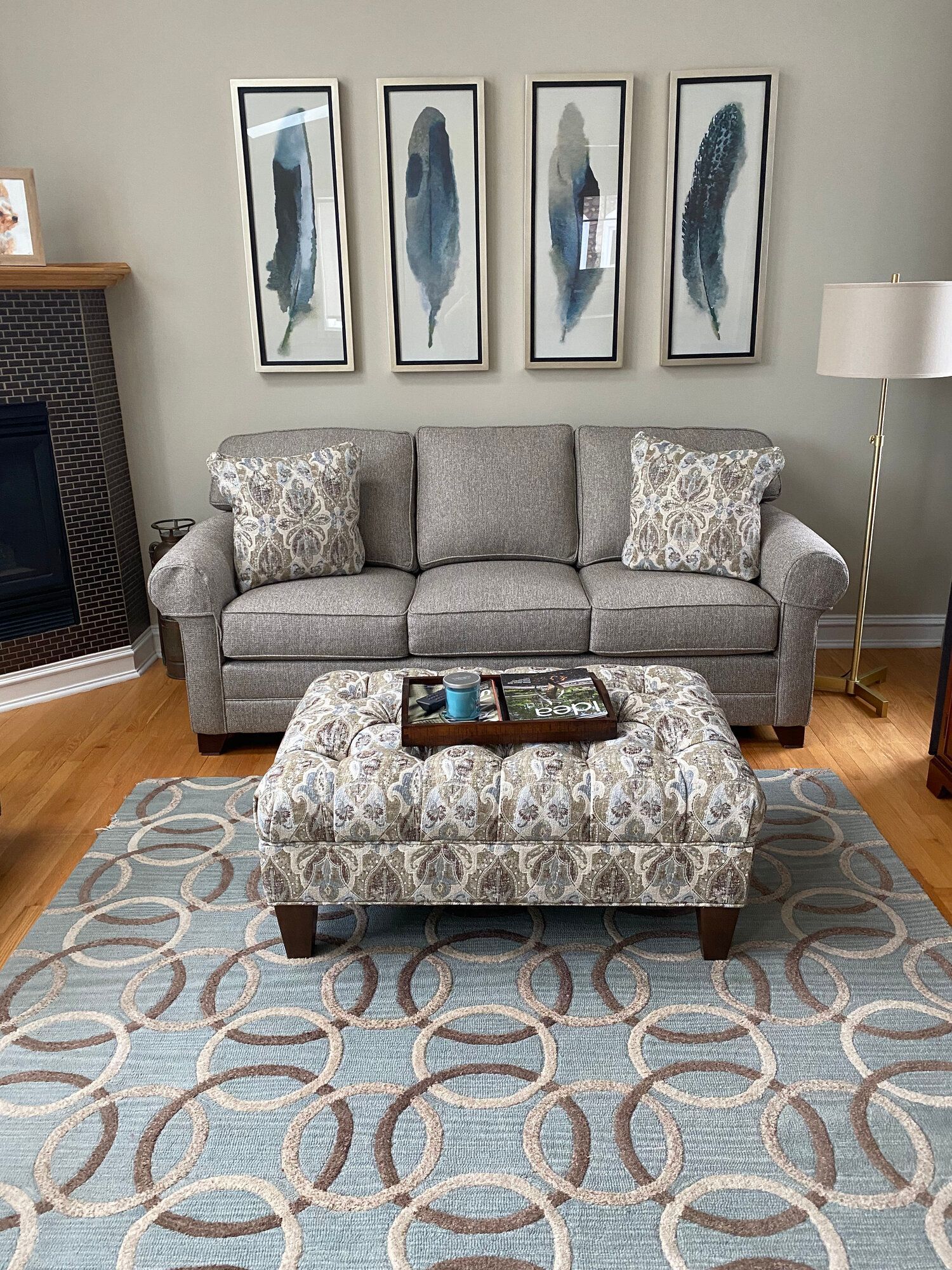 A living room with a couch , ottoman , rug and fireplace.