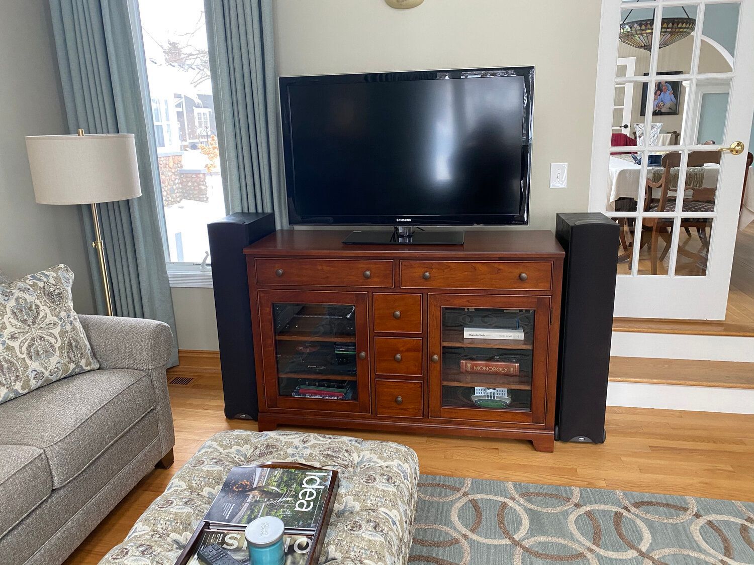 A living room with a large flat screen tv on a wooden entertainment center.