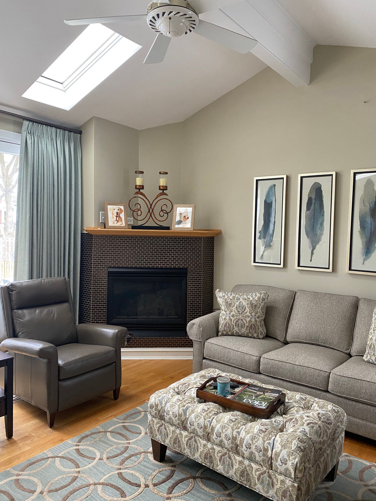 A living room with a couch , chair , ottoman and fireplace.