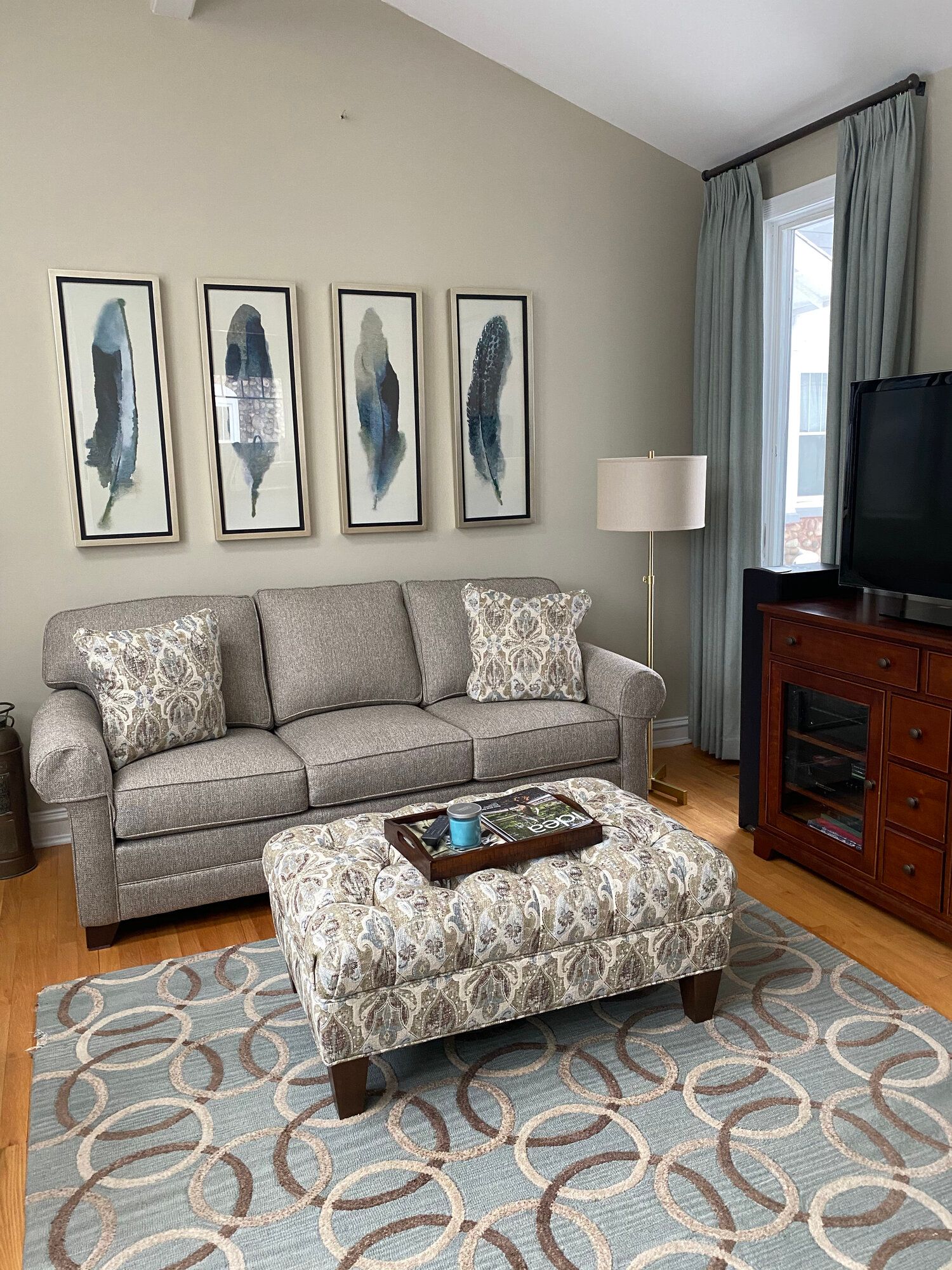 A living room with a couch , ottoman , coffee table and television.