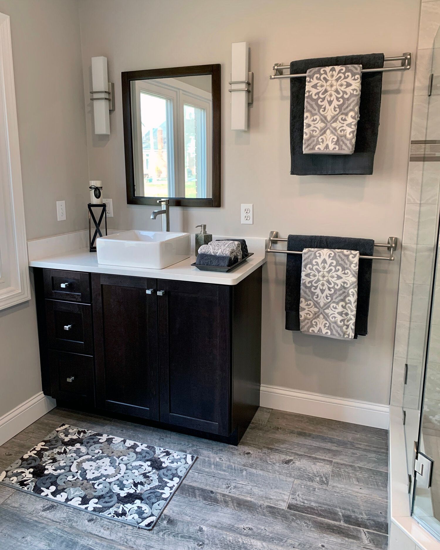 A bathroom with a sink , mirror , and towels hanging on the wall.