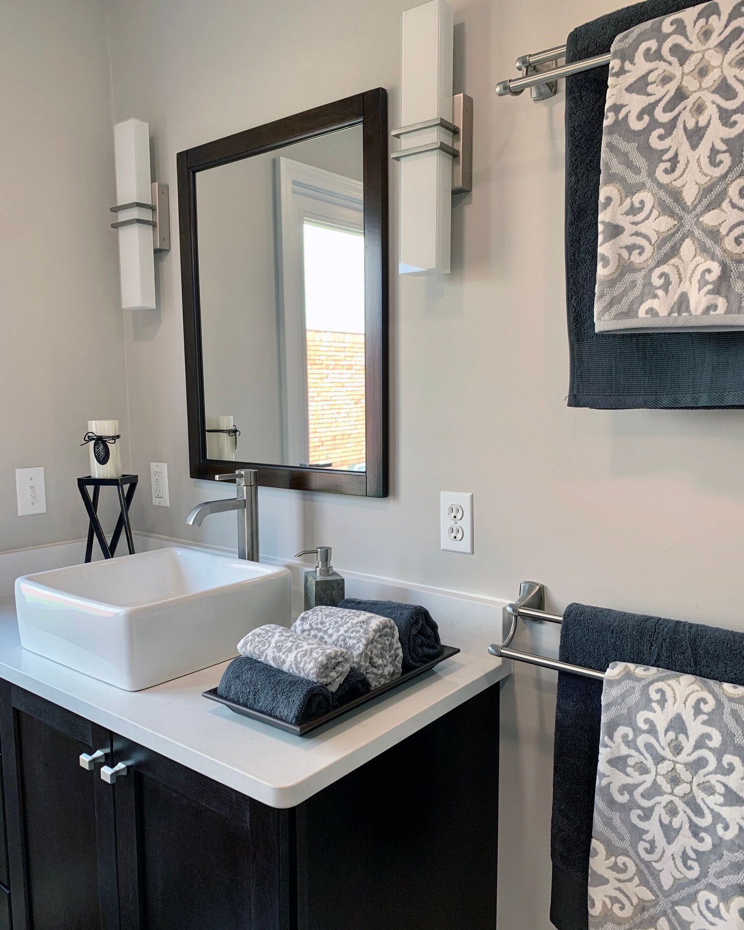 A bathroom with a sink , mirror and towels on the counter.
