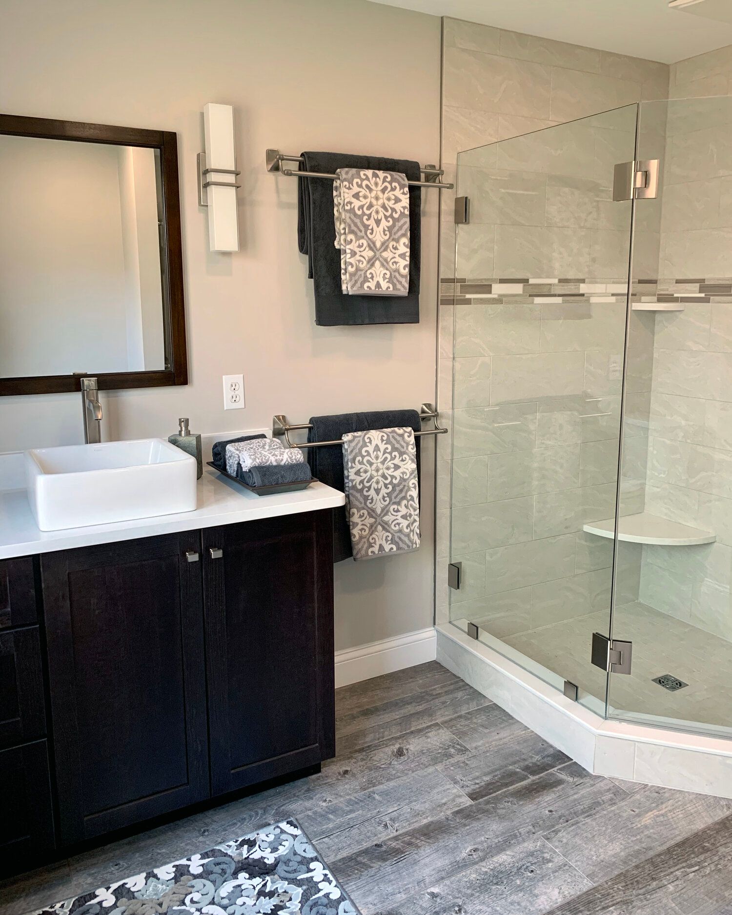 A bathroom with a sink , mirror , and walk in shower.