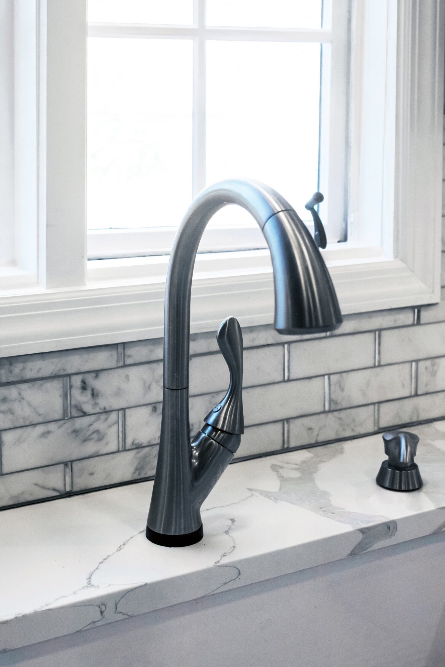 A kitchen sink with a faucet and a window