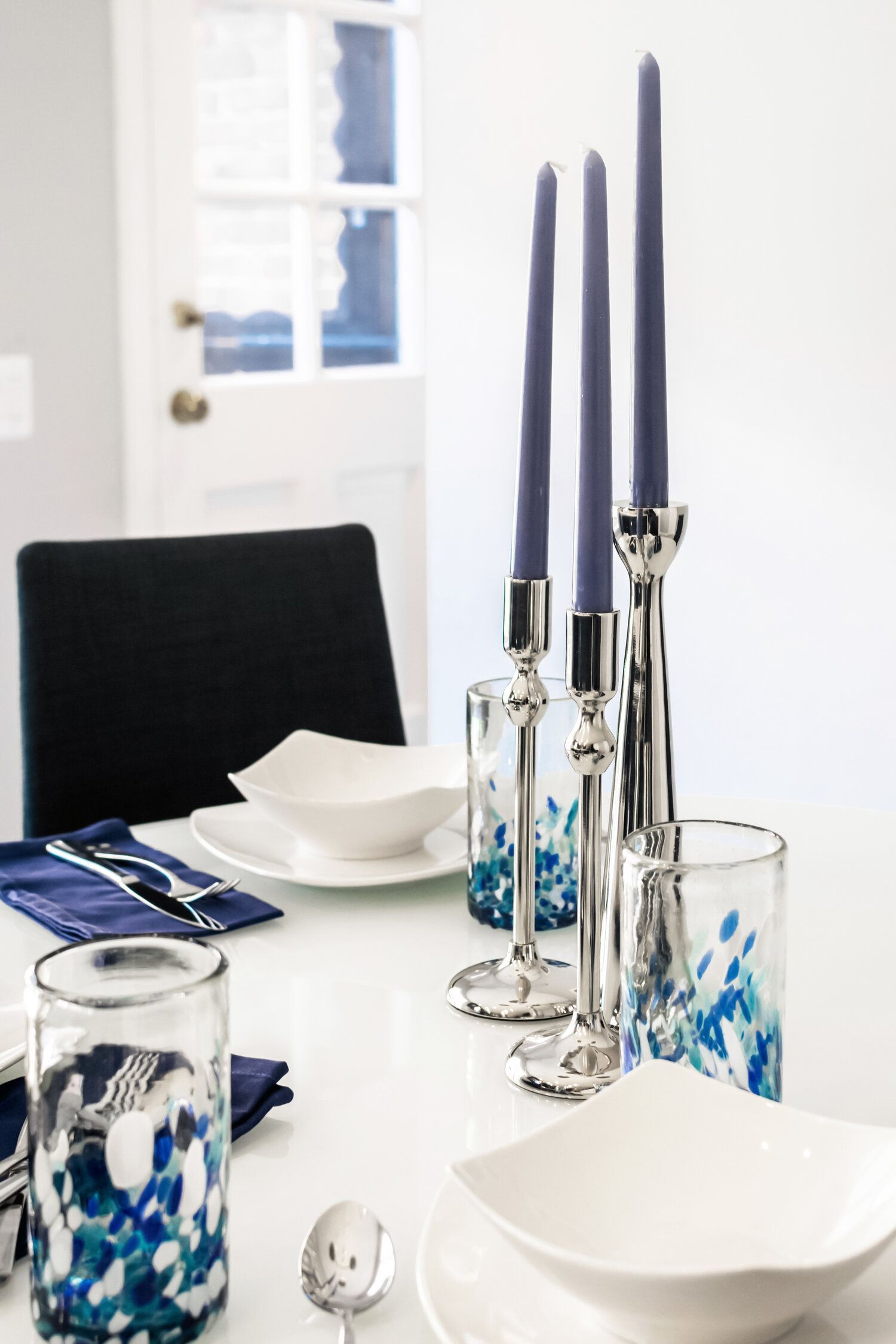 A dining table with plates bowls and candles on it