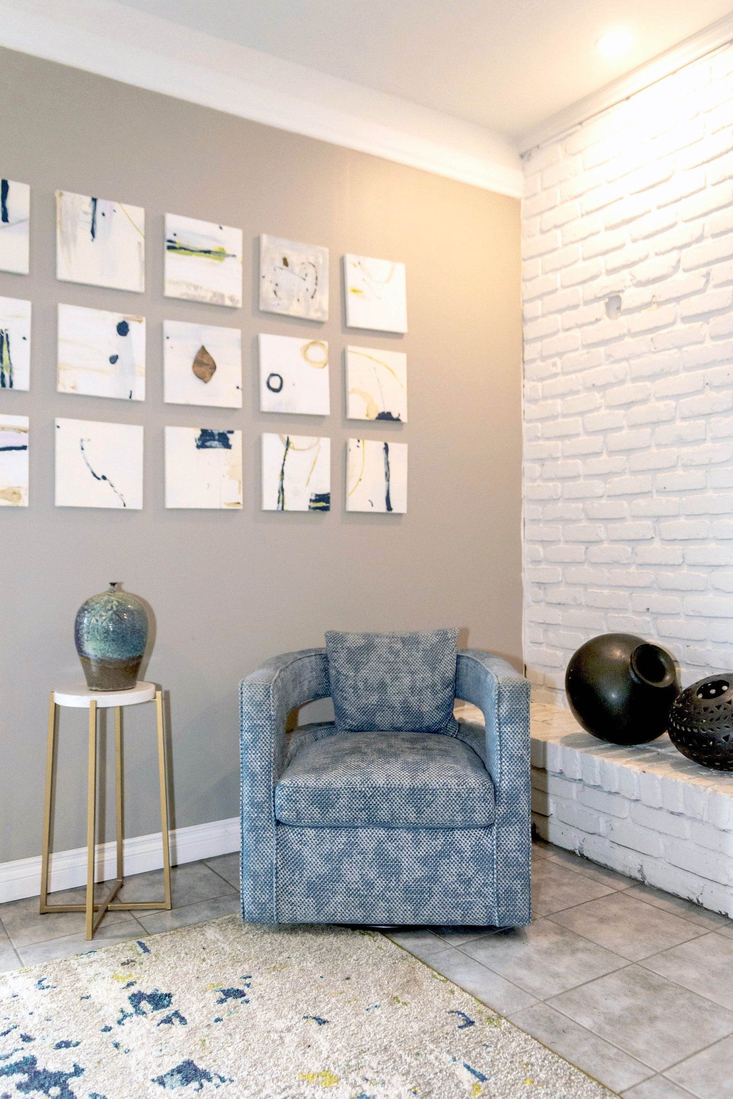 A living room with a chair , vases and paintings on the wall.