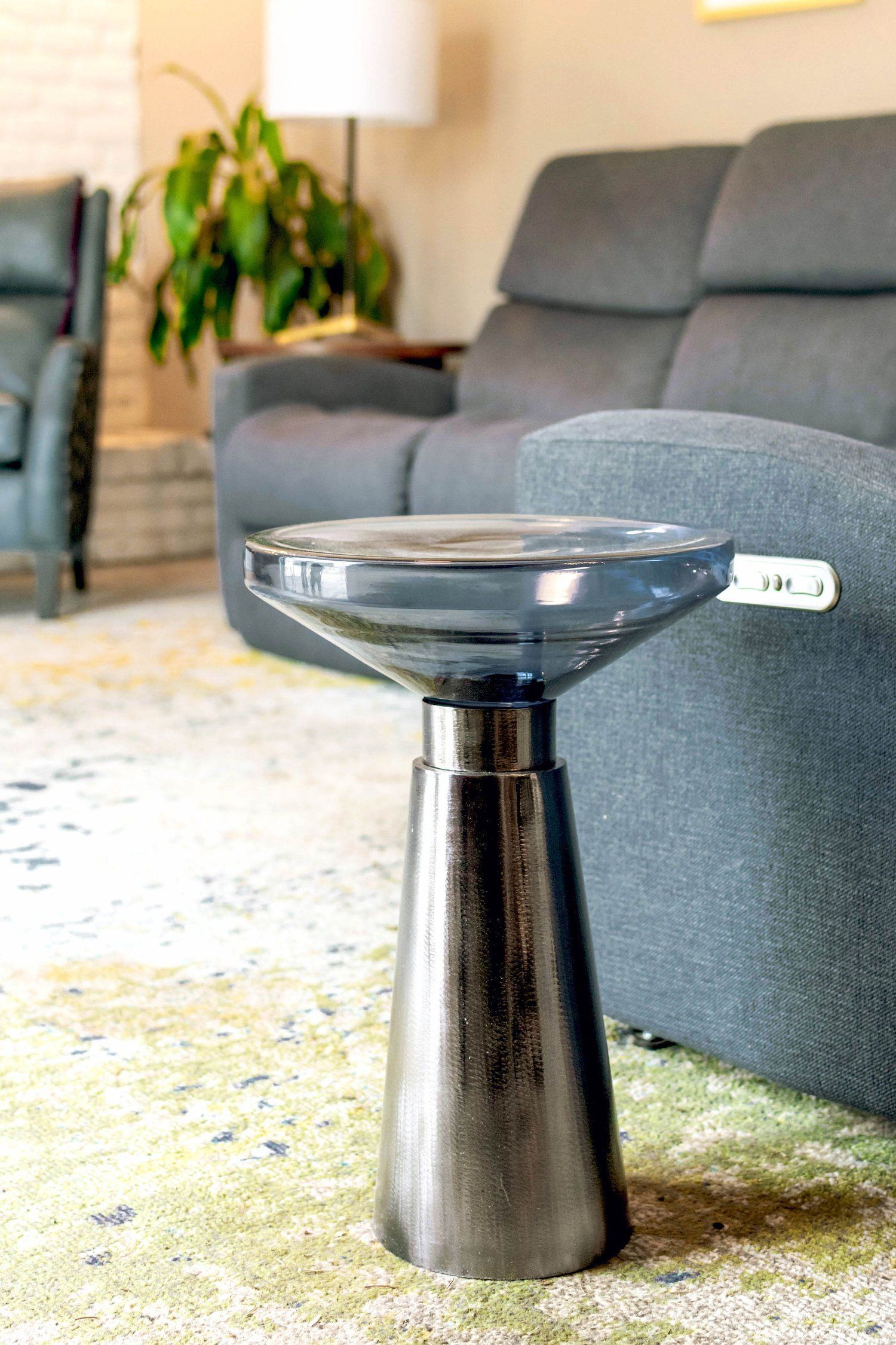 A small table with a glass top is sitting in a living room next to a couch.