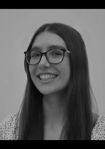 Woman smiling, wearing glasses and a dotted top.