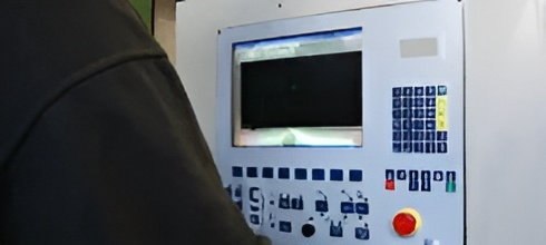 Una persona sta lavorando su una macchina dotata di monitor e pulsanti.