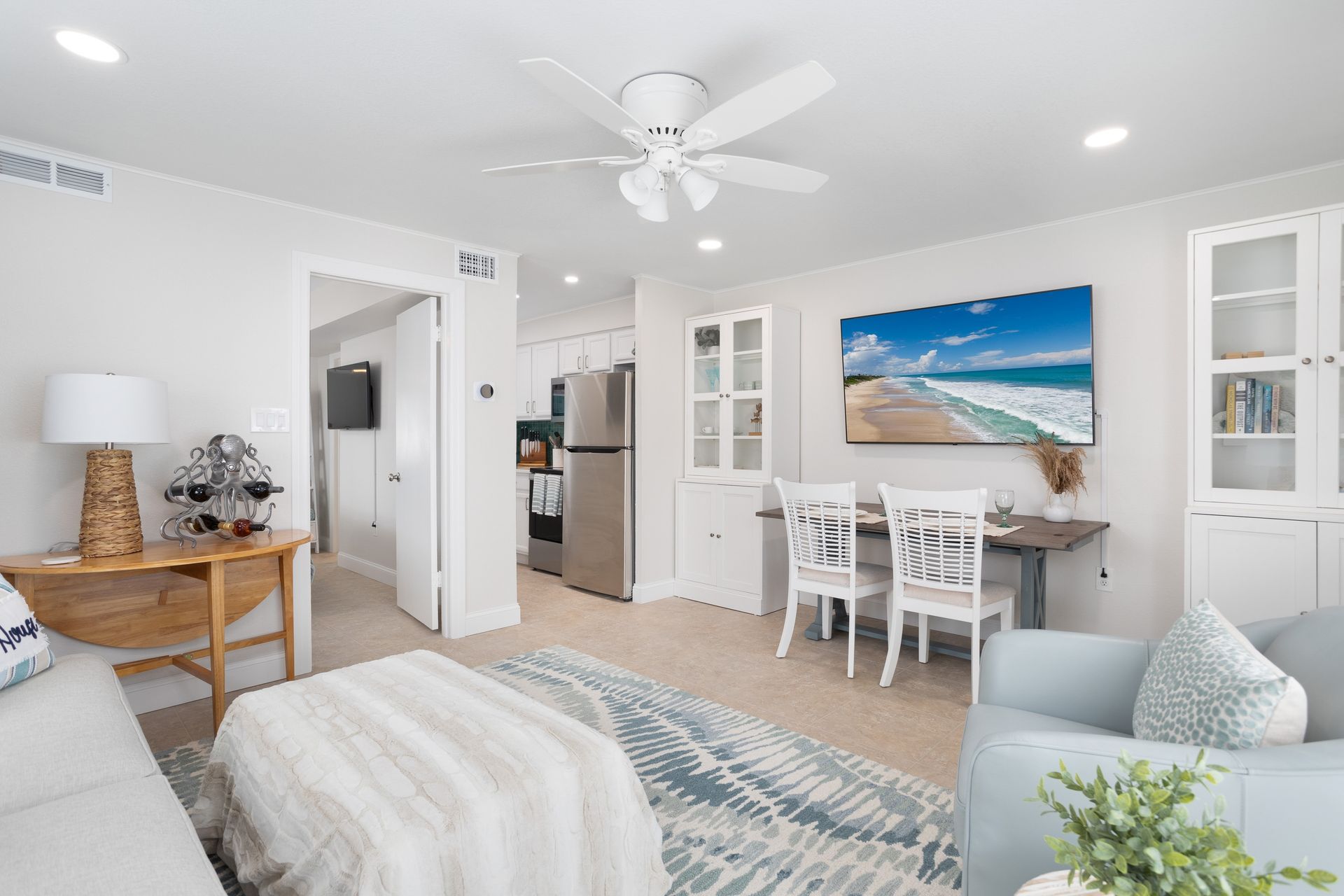 Cozy living space with light blue accents, including a sofa, chairs, and rug, beach artwork.
