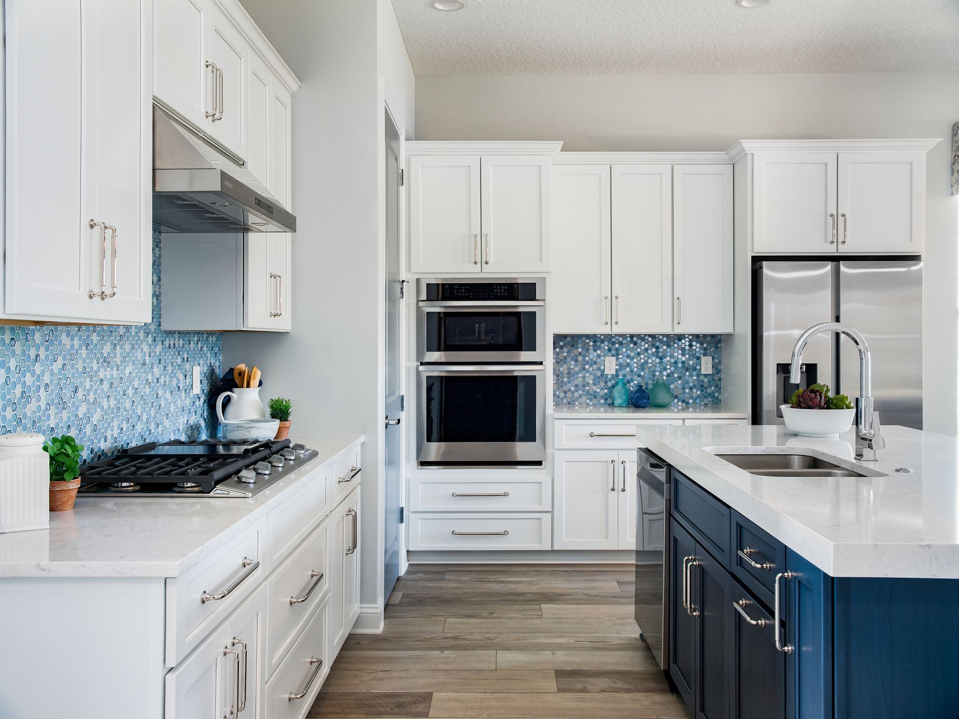 White kitchen with blue mosaic backsplash, stainless steel appliances, and navy blue island.