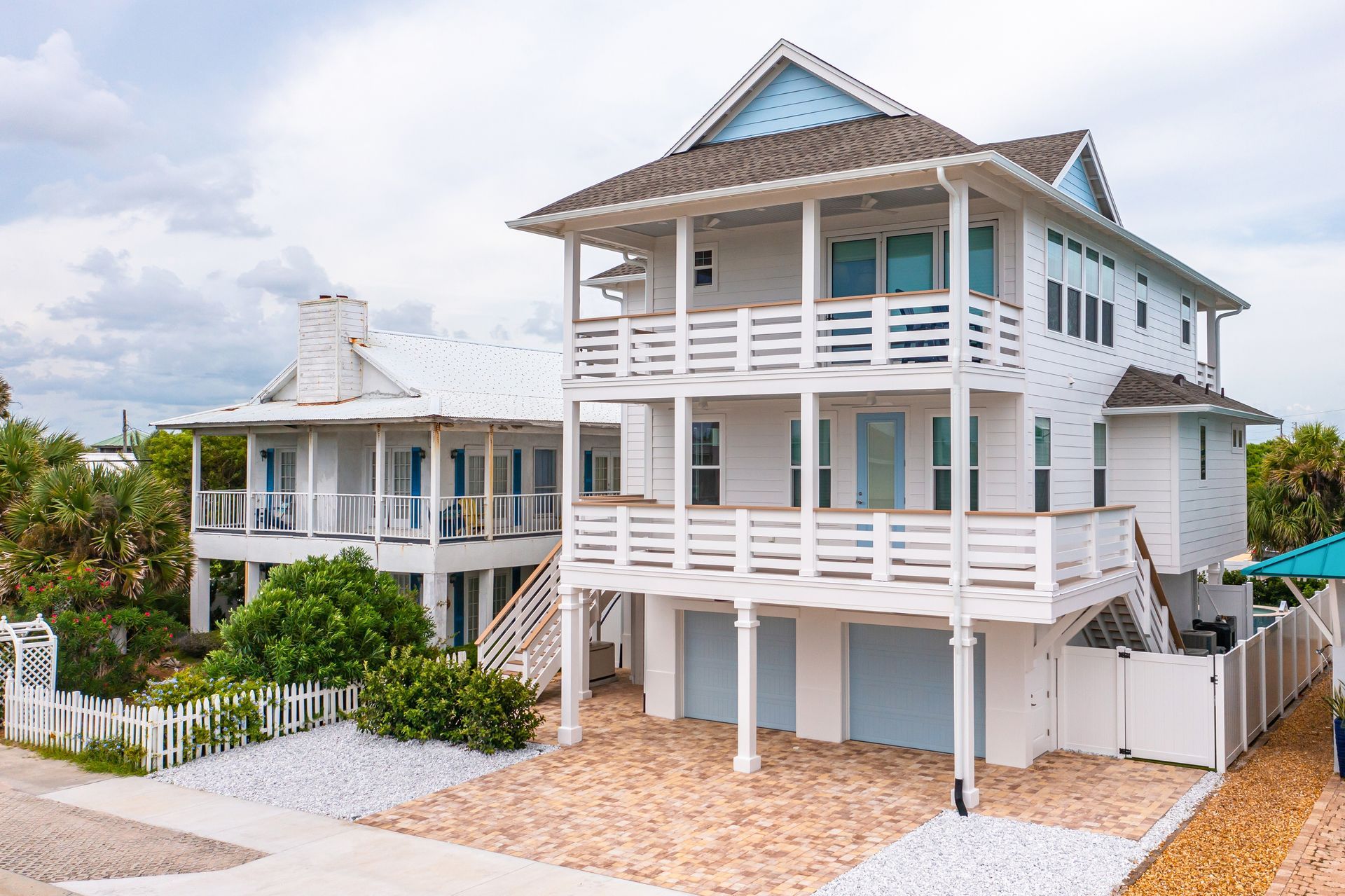 White beach house with balconies, light blue accents, and tiled roof.