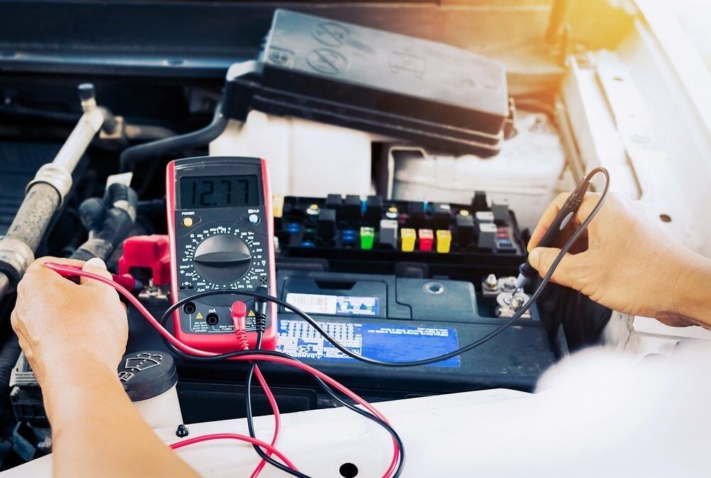 Hands Testing a Car Battery With a Multimeter — Direct Current Solutions in Mareeba, QLD