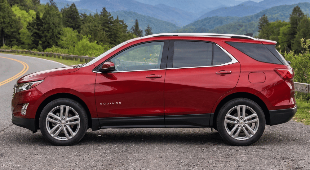 Red SUV parked on a mountain road with forested hills in the background