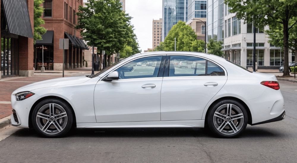 White sedan parked on a city street with modern buildings in the background