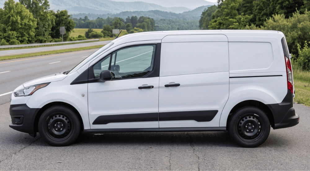 White cargo van parked on a roadside with mountains and greenery in the background