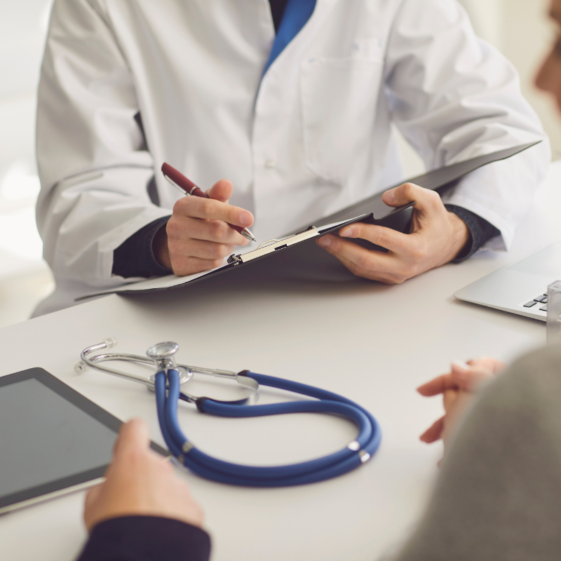 A doctor is talking to a patient while holding a clipboard and a stethoscope
