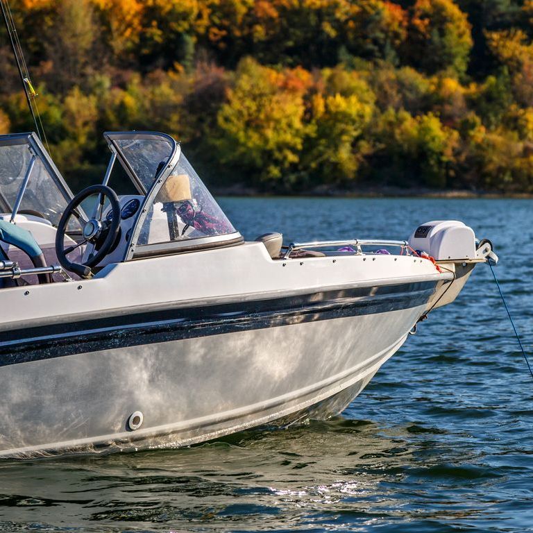 A boat is floating on a lake with trees in the background.