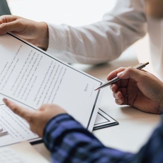 A person is holding a pen over a piece of paper