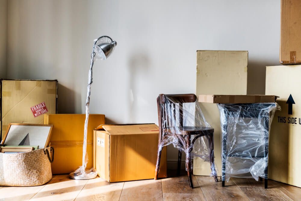 A Room Filled With Boxes, Chairs And A Lamp — Uplift Removals in Burdell, QLD