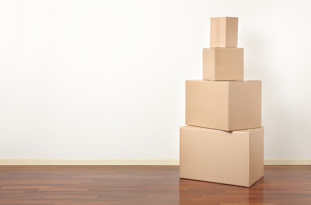 A Stack Of Cardboard Boxes Sitting On Top Of Each Other On A Wooden Floor — Uplift Removals in Sunshine Coast, QLD