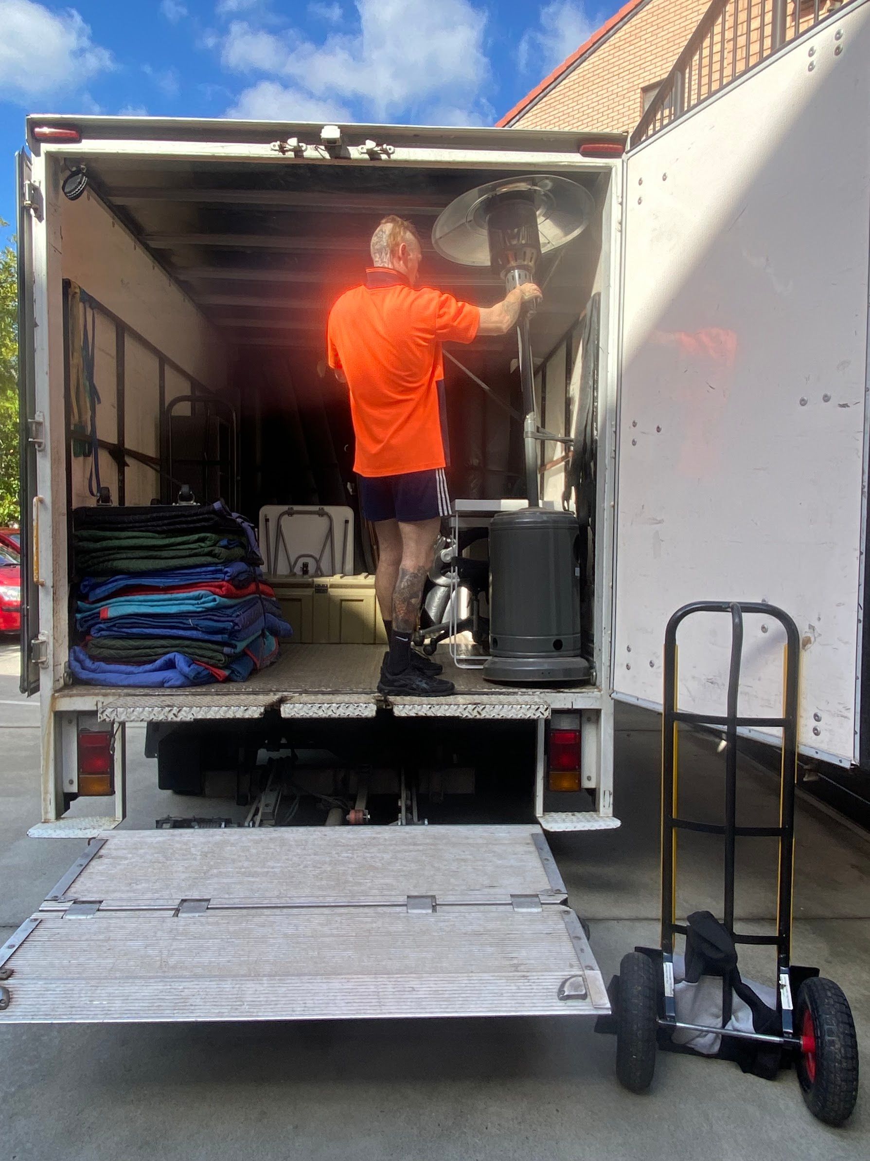 Two Movers Wrapping Furniture in Plastic Wrap Inside a Room With Boxes — Uplift Removals in Brisbane, QLD