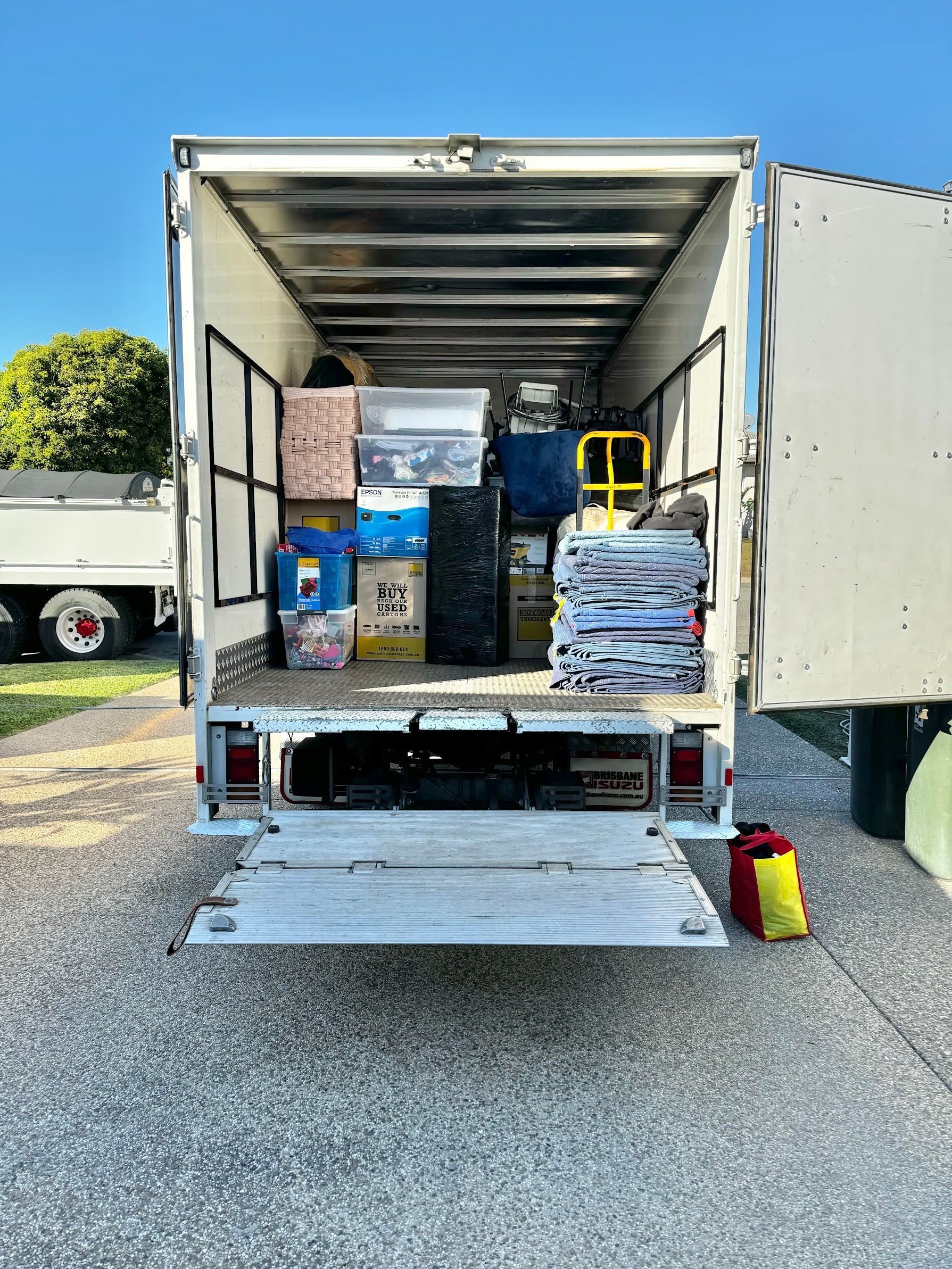 A Man Is Standing In The Back Of A Moving Truck — Uplift Removals in Burdell, QLD