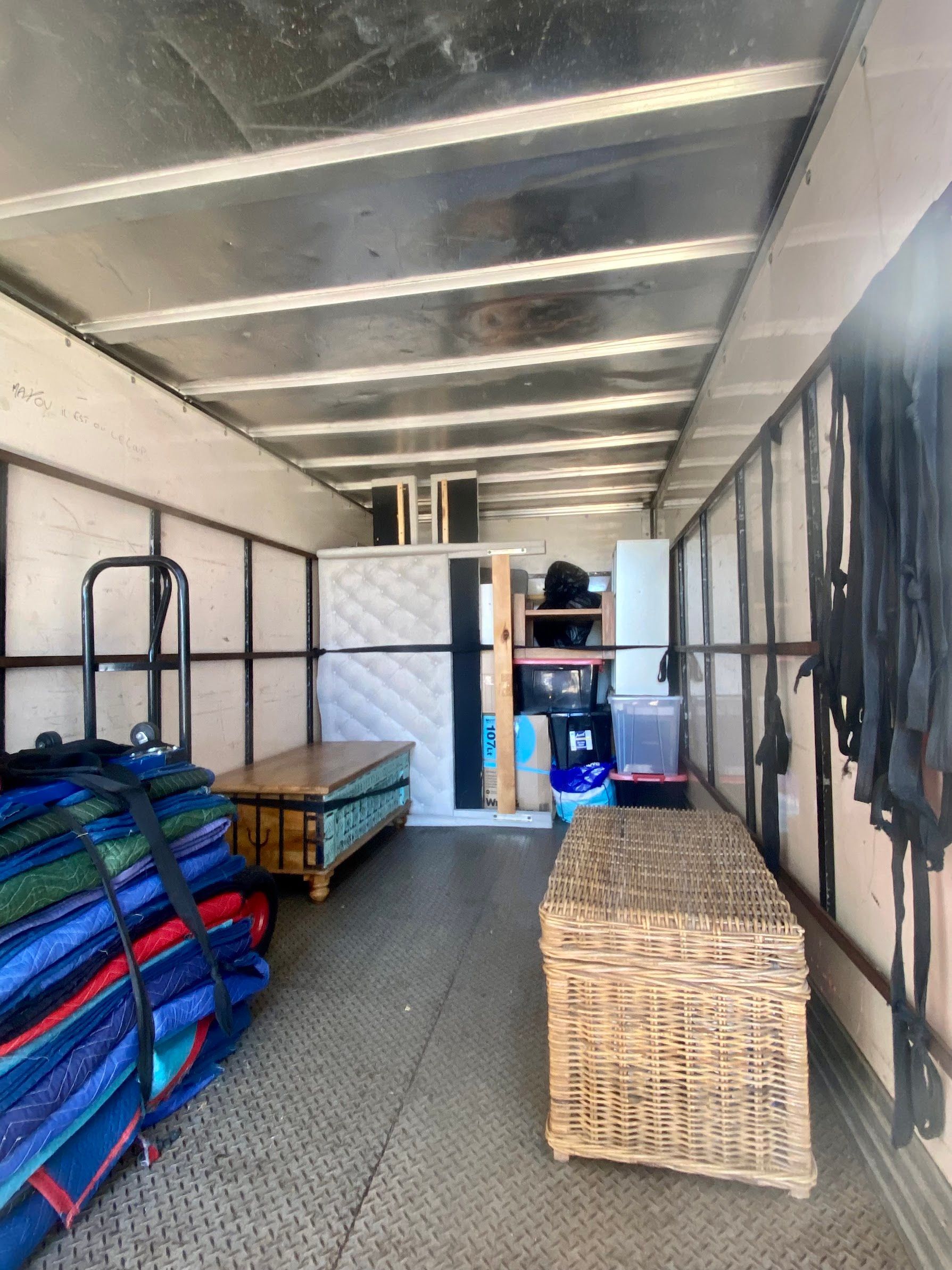 Two Movers Wrapping a Sofa, Woman Watches in a Room With Boxes and Windows — Uplift Removals in Ipswich, QLD