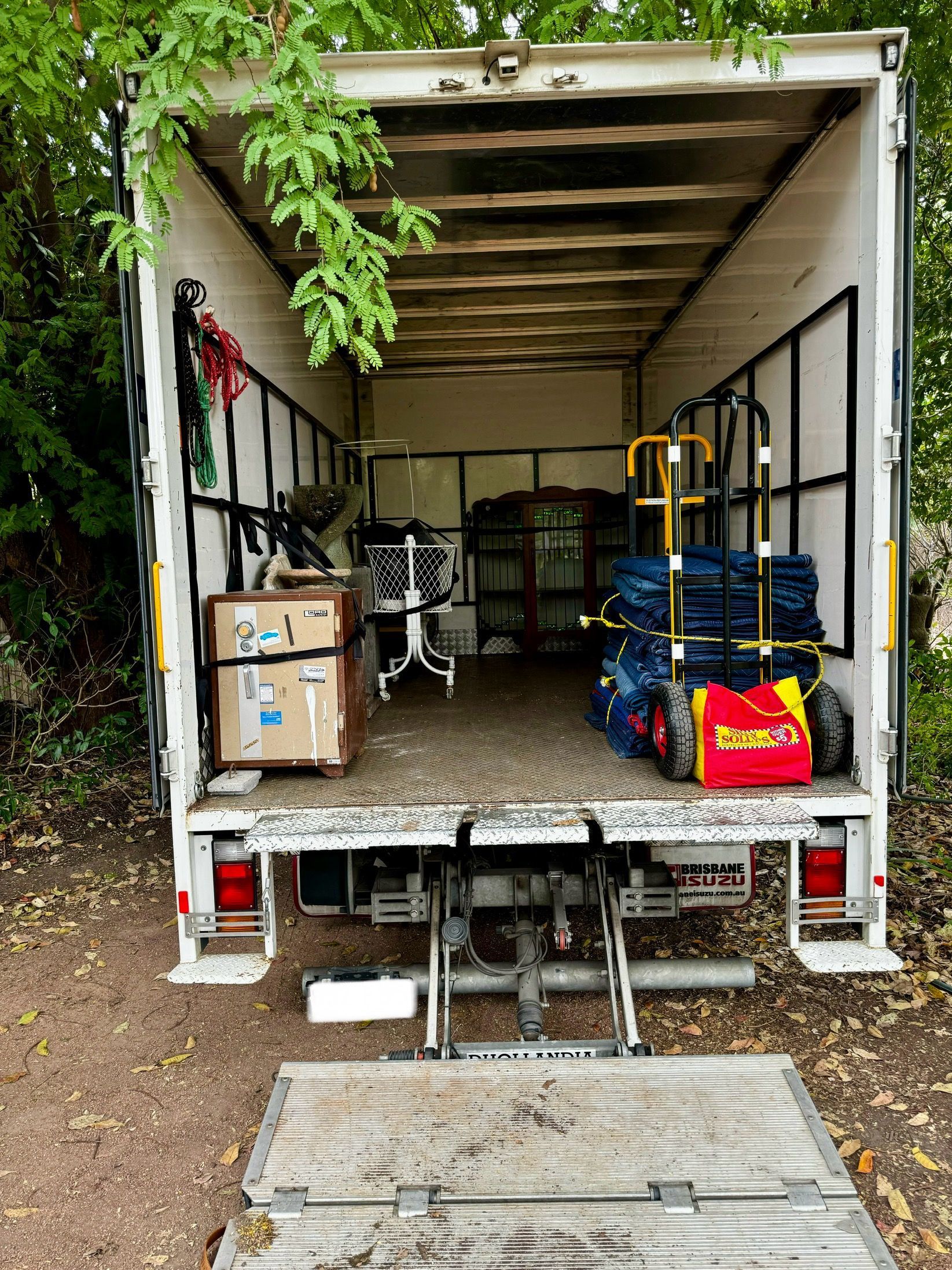 A Man Is Standing In The Back Of A Moving Truck — Uplift Removals in Burdell, QLD