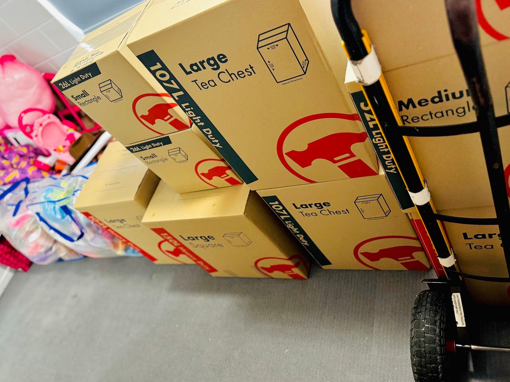 Pile of Stacked Cardboard Moving Boxes in a Bright, Empty Room Next to a Window — Uplift Removals in Gold Coast, QLD