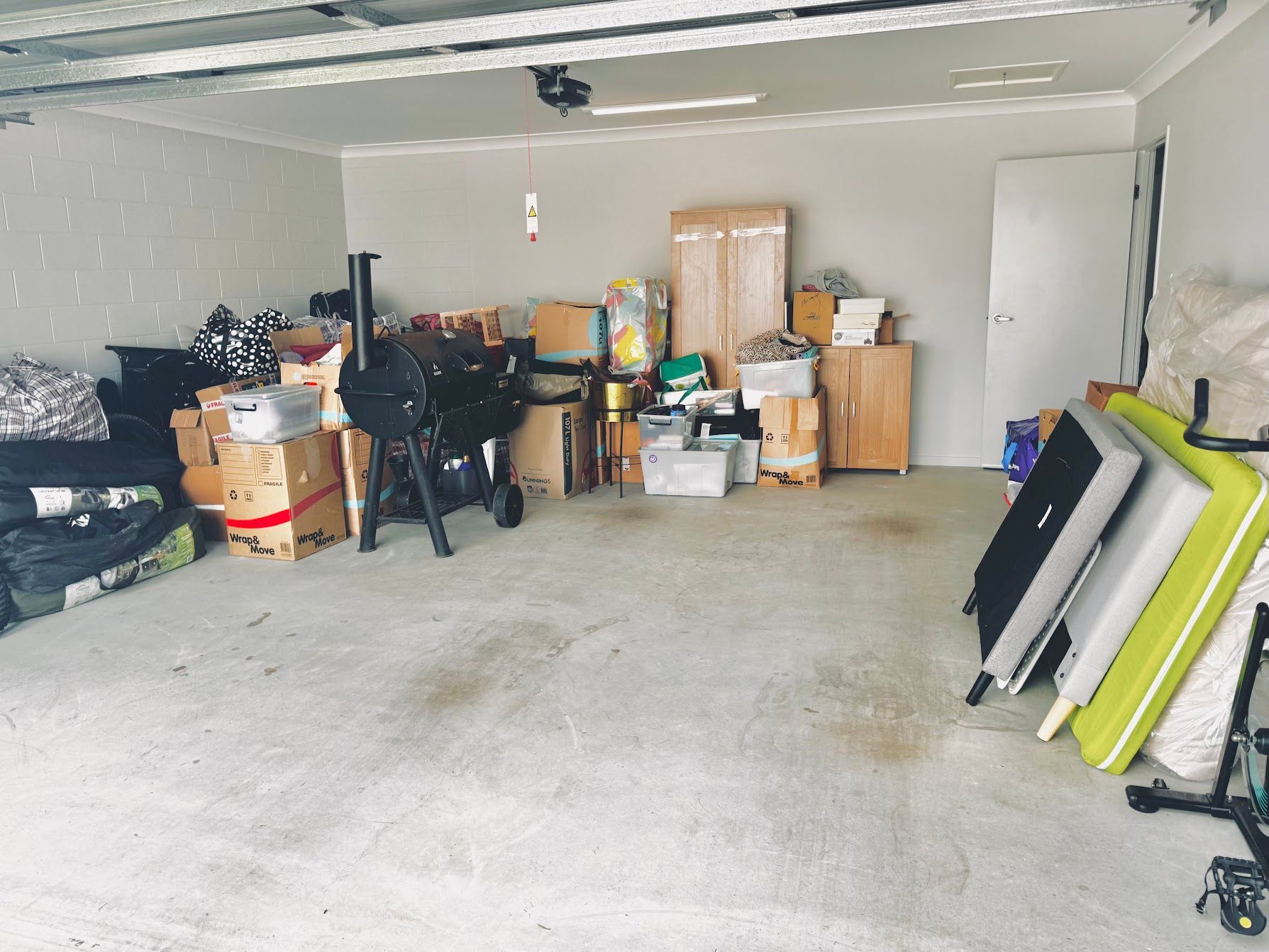 Two Movers Lift a Wrapped Sofa in a Room With Boxes and Furniture — Uplift Removals in Gold Coast, QLD