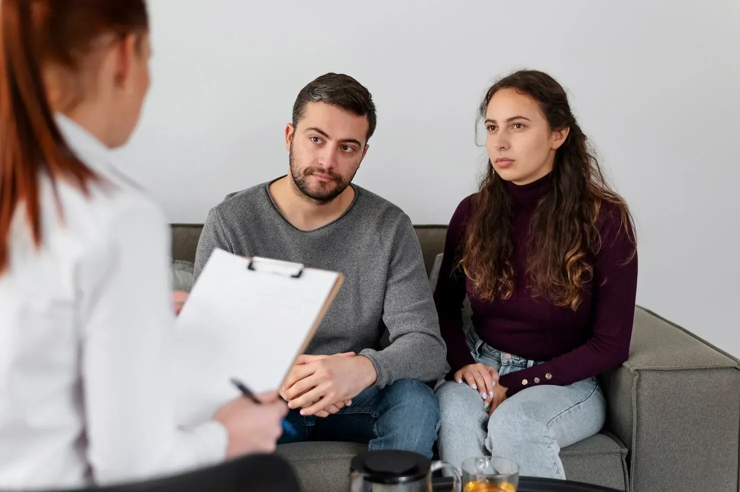 Therapist speaking with two seated clients in a counseling session