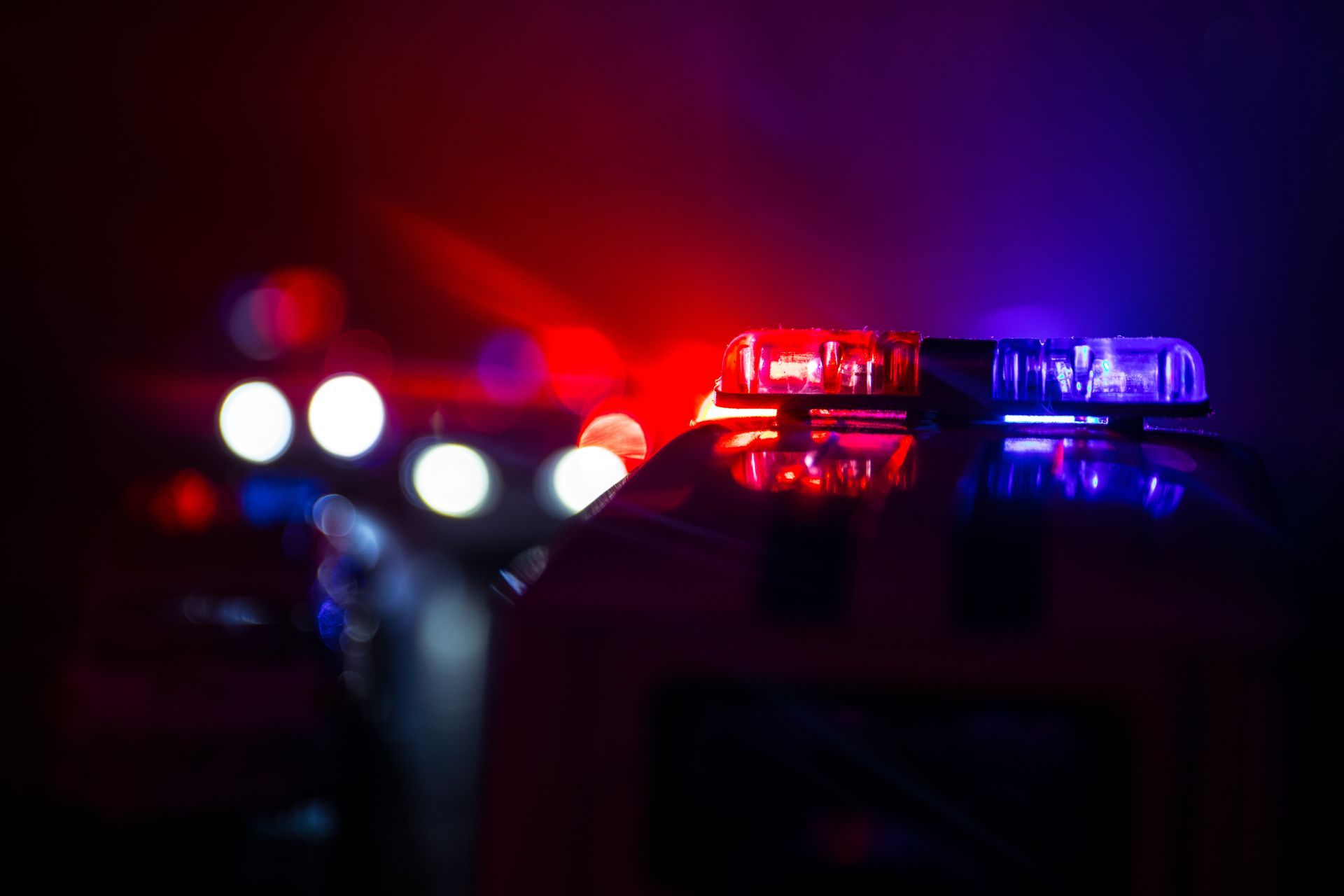 Police car lights flashing red and blue in the dark at night.