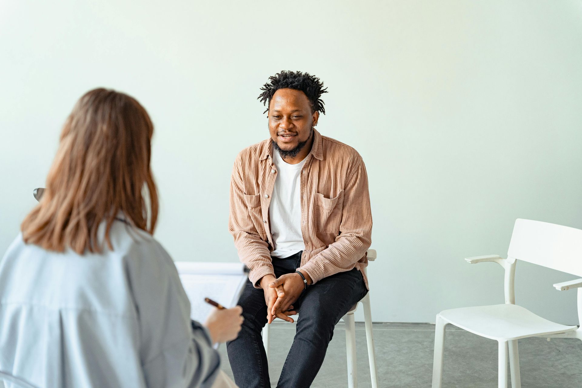 A man is sitting in a chair talking to a woman.