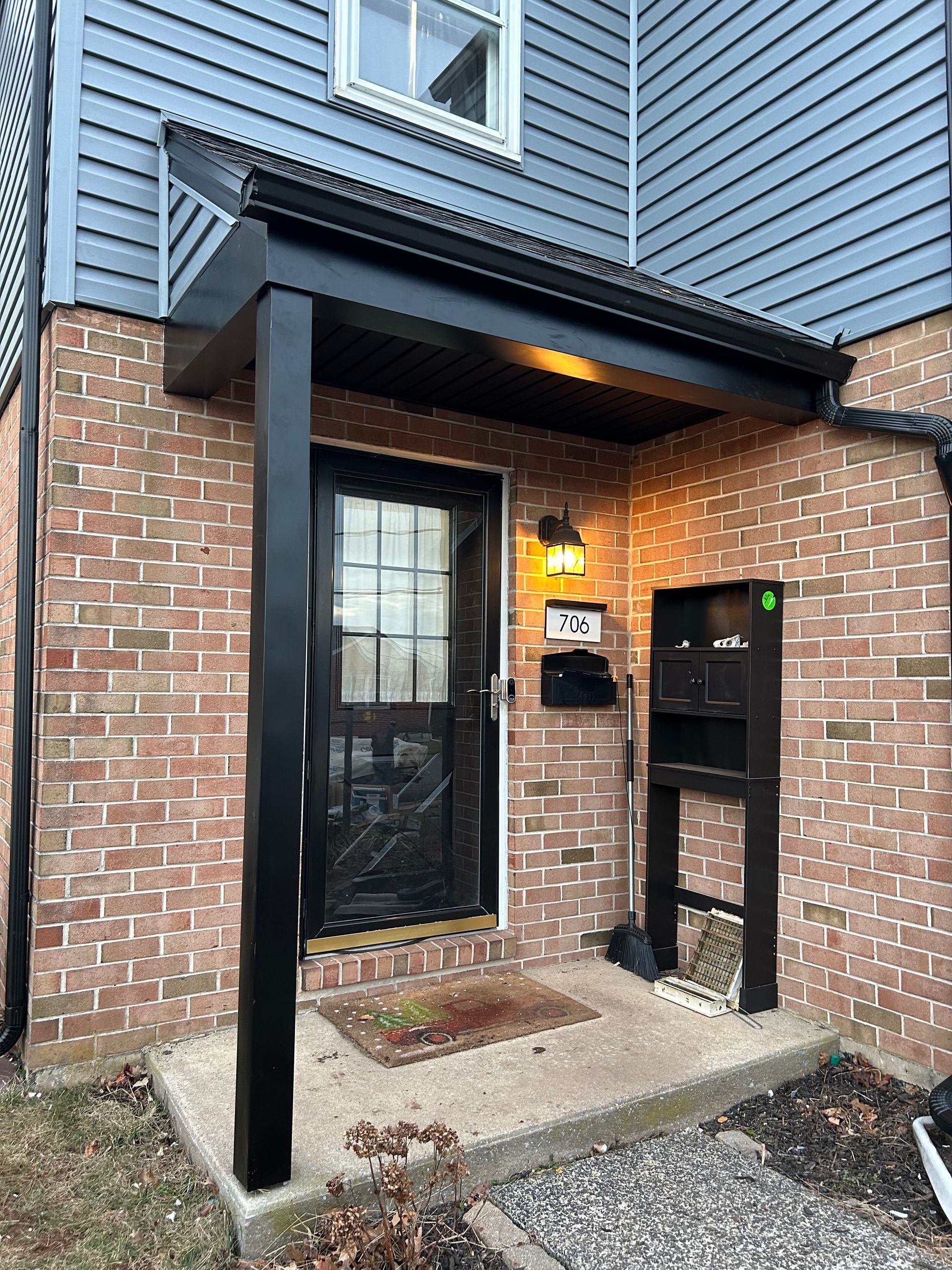 New black entryway door on a bring home with new blue siding.