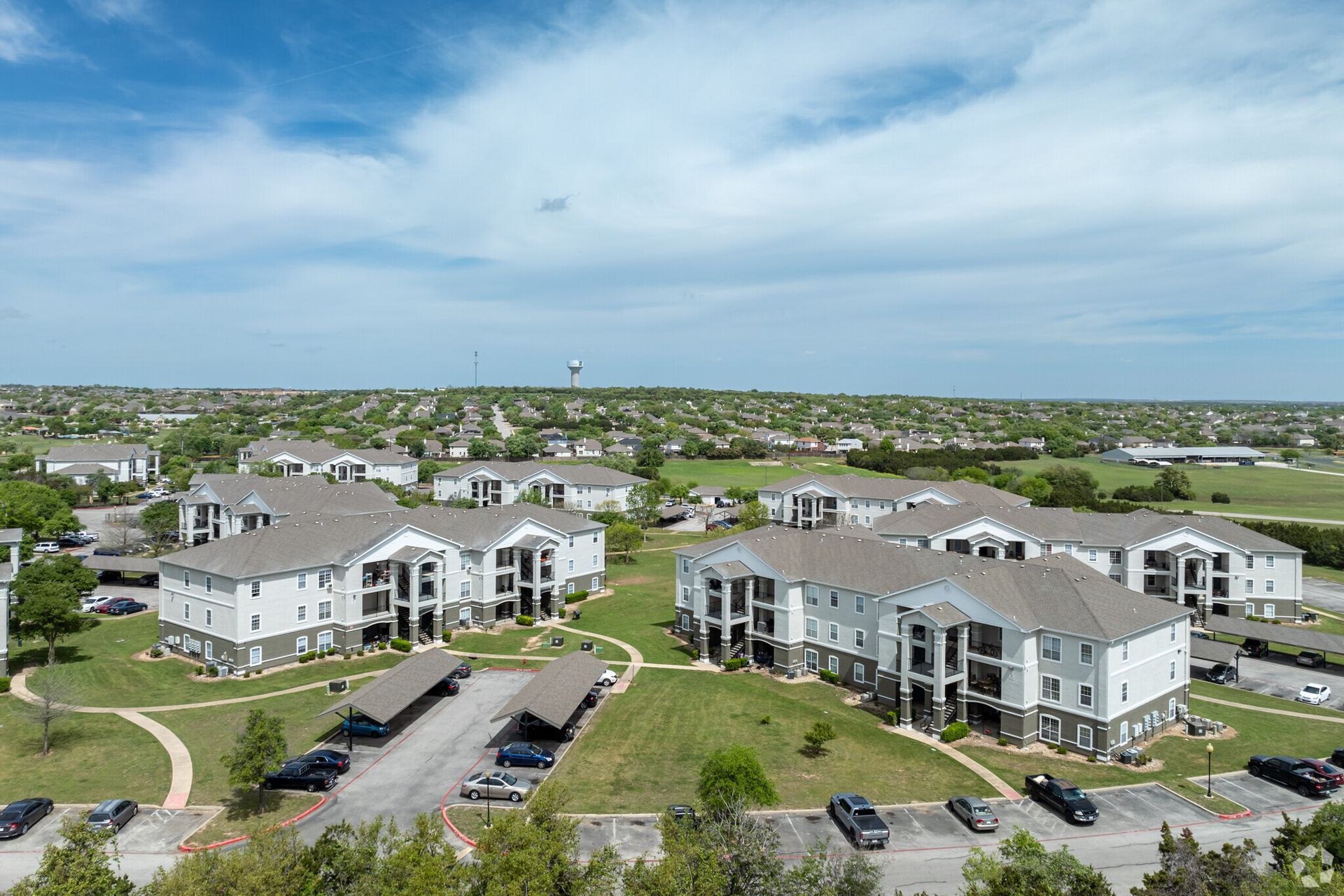An aerial view of a large apartment complex with cars parked in front of it.