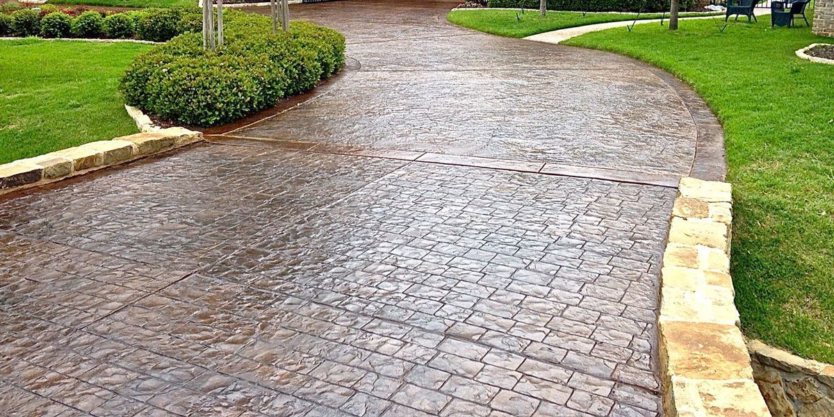 Wet cobblestone garden path curving through green lawns with low stone edging