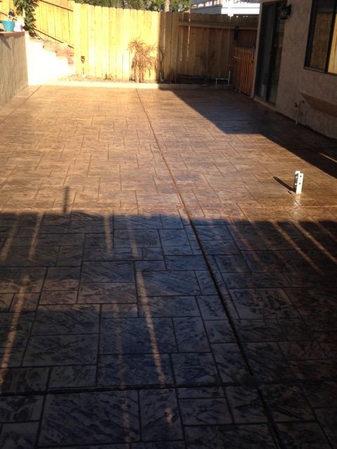 Sunny tiled patio with wooden fence and a small white pipe on the right side