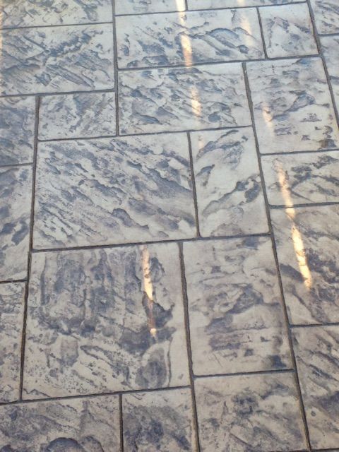 Stone-patterned tiled pavement with light and dark gray marbling and a few sunlit streaks