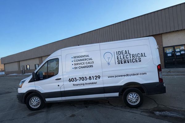 White Ideal Electrical Services van parked outside a warehouse building.