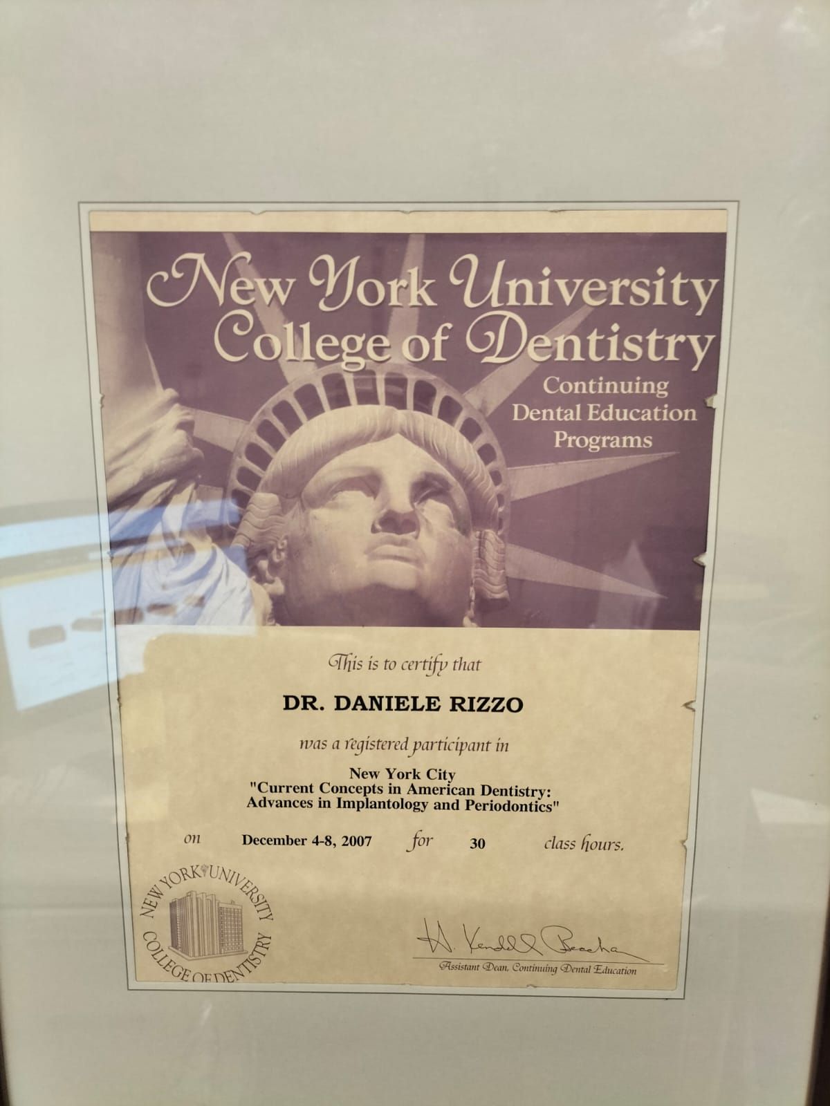 Certificato incorniciato del College of Dentistry della New York University con ritratto e intestazione decorativa color bordeaux.