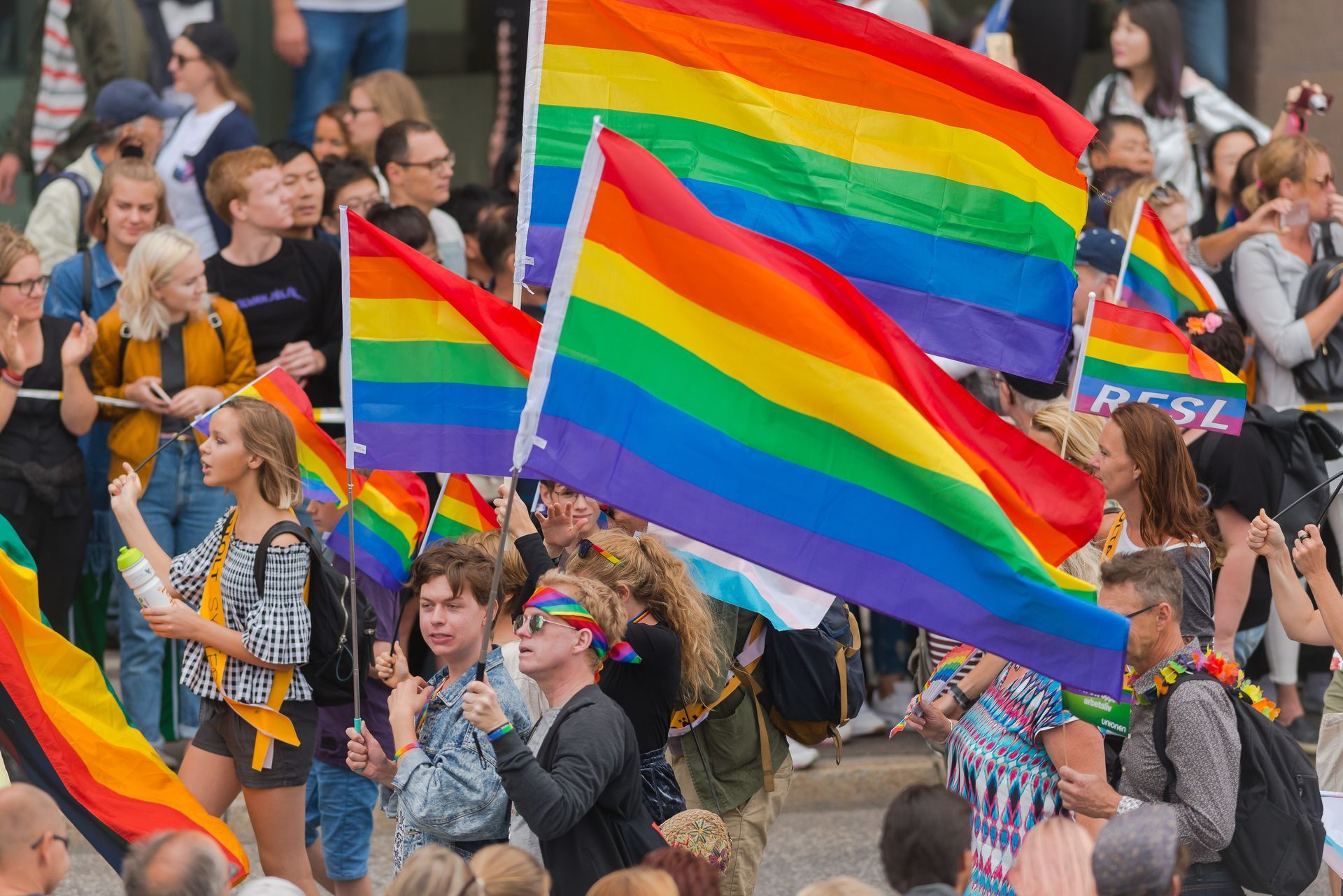 People holding rainbow flags at a Pride parade, celebrating LGBTQ+ rights.